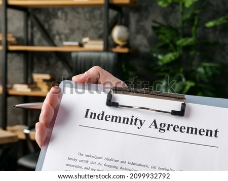 Hand holds indemnity agreement for signing in the office. Royalty-Free Stock Photo #2099932792