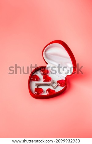 Key in a box of heart shape as a symbol of love. Valentines day background. Greeting card with red heart on pink background