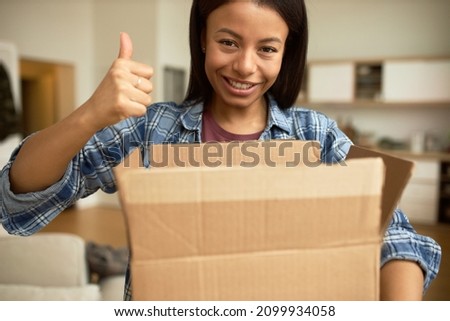 Happy cute woman showing thumb up holding unpacked carton parcel, satisfied and pleased with fast delivery service in time and quality of ordered goods. Human emotions, signs, gestures