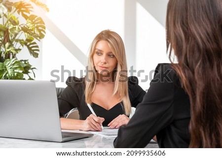 Two office women in business room working together, laptop on desk. Recruitment interview, contract signing in financial company. Concept of career development and partnership