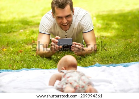 Father with baby In Park  taking selfie by mobile phone