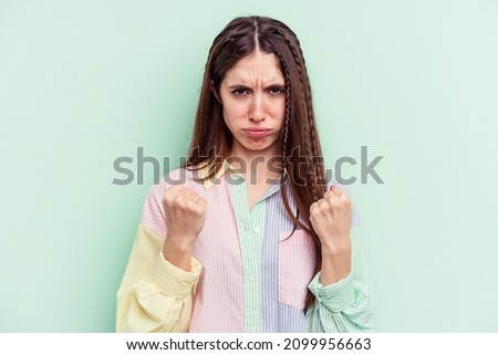 Young caucasian woman isolated on green background upset screaming with tense hands.