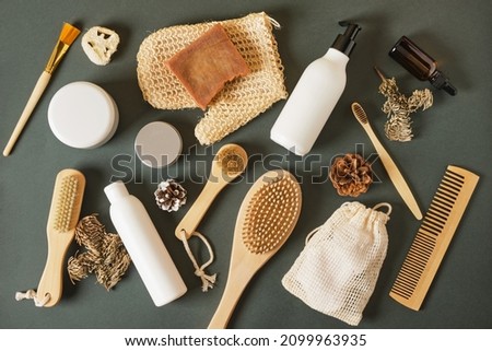 eco friendly body care set on green background top view, various skin care products, bottles without labels and wooden massage brushes, natural winter care concept