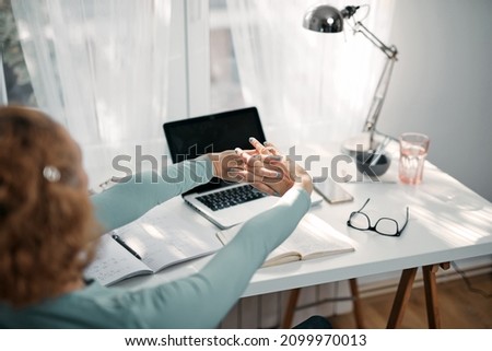 Woman with hand, joint, arm and finger pain, stretching and massaging during work on a laptop.