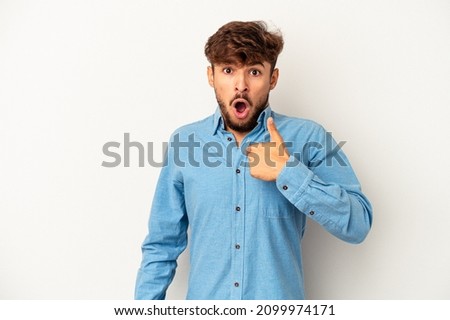 Young arab man isolated on grey background surprised pointing with finger, smiling broadly. Royalty-Free Stock Photo #2099974171