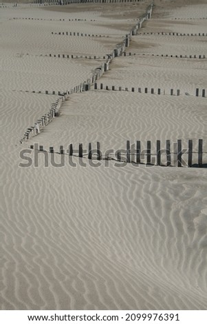 wooden barrier sunk into the sands of a dune by the sea