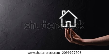 Male hand holding house icon on blue background. Property insurance and security concept.Real estate concept.Banner with copy space