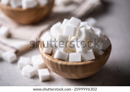White sugar cubes in a wooden bowl on the table.