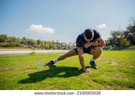 Attractive and handsome guy is exercising his stretching routine in the park