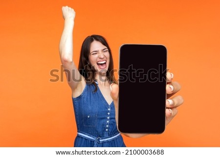 Portrait of happy joyful girl screaming with happiness showing mobile advertisement mockup area and celebrating her victory. indoor studio shot isolated on pink background Royalty-Free Stock Photo #2100003688