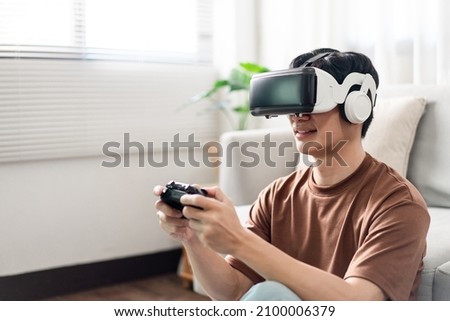 Technology Concept A man putting on a virtual reality headset and pressing a black console game while sitting on the floor.