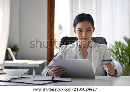Attractive businesswoman holding credit card and making banking online with digital tablet.