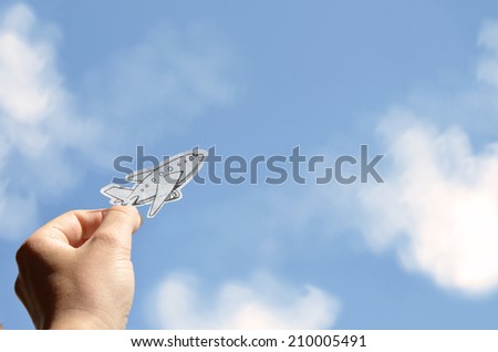 Hand holding a picture of plane on a sky background