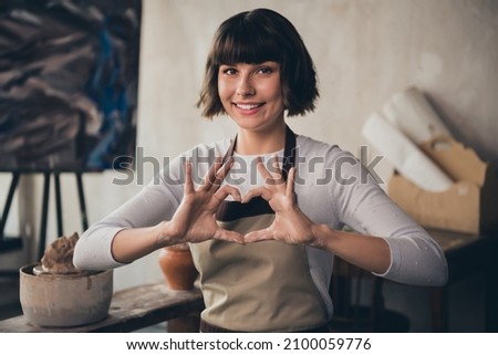 Photo of self-employed lady small store owner potter make heart shape enjoy life vocation hobby sit in workroom