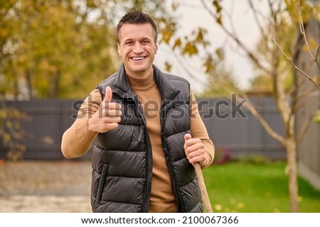 Man standing in garden showing ok gesture looking at camera
