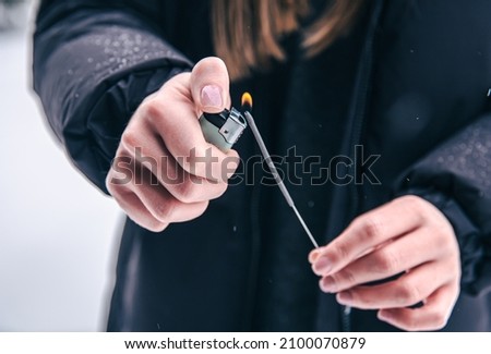 Close-up of a woman setting fire to a sparkler with a lighter.