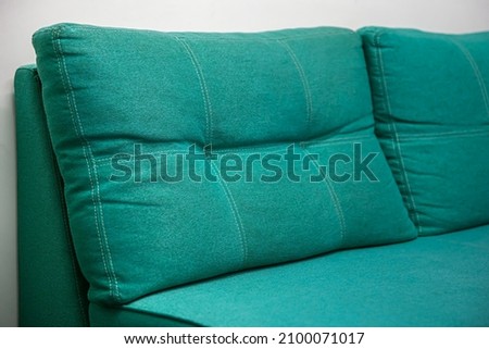 Closeup of turquoise sofa with large pillows.