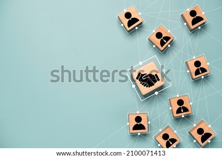Top view design on blue background of Hand shaking which print screen on wooden cube block which connection with human icon for business deal and agreement concept. Royalty-Free Stock Photo #2100071413