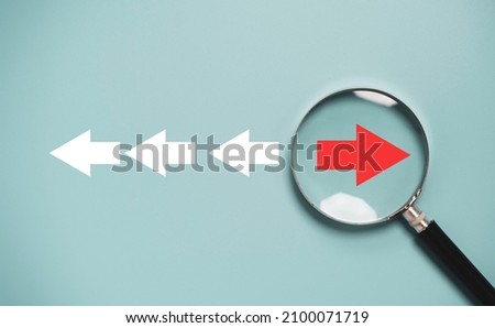 Red arrow inside of magnifier glass and different direction from white arrow for focus business disruption and technology transformation concept.