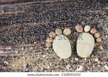 Funny human footprints from stones on a wooden background.