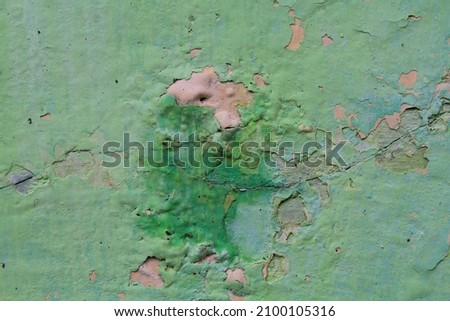 The texture of the damaged wall paint is peeling moldy, Close-up. Badly fixed building facade wall covered with cracks in stucco and paint. Missing patch of paint in the middle; crack with flappy peel