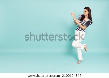 Young elegant beautiful Asian woman smiling and pointing to empty copy space isolated on green background, Full body composition Royalty-Free Stock Photo #2100124549