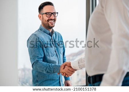 Businessman greeting job applicant businessmen handshaking over signed contract handsome entrepreneur handshake with a colleague cheerful young manager handshake with new employee getting a deal done Royalty-Free Stock Photo #2100151378