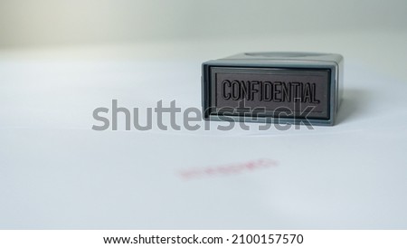 Close up rubber stamping that says confidential and secret information document leak or data Royalty-Free Stock Photo #2100157570