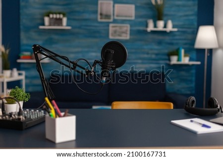 Empty home recording studio with podcast equipment. Professional microphone and headphones used for online broadcast on social media. Electronic audio livestream technology on desk.
