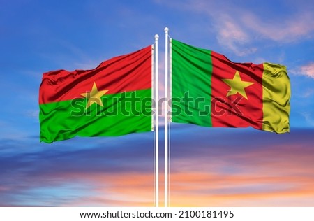 Cameroon and Burkina Faso two flags on flagpoles and blue cloudy sky  Royalty-Free Stock Photo #2100181495