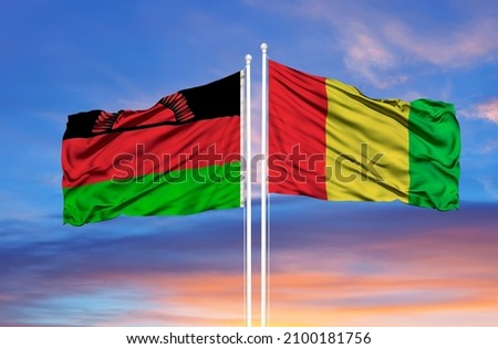 Guinea and Malawi  two flags on flagpoles and blue cloudy sky  Royalty-Free Stock Photo #2100181756