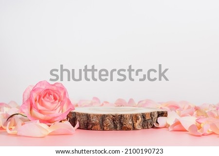 Wooden podium with pink rose and petals to demonstrate products, cosmetics and gifts. Valentine, mother day and women day concept Royalty-Free Stock Photo #2100190723