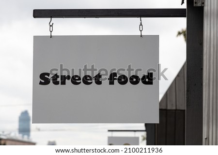 The gray sign with black lettering Street food is hanging outside