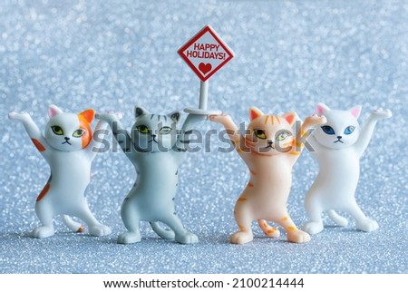 Four cute toy kittens with a road sign that says happy holidays. Blue sparkling background. Happy holiday concept. Close-up