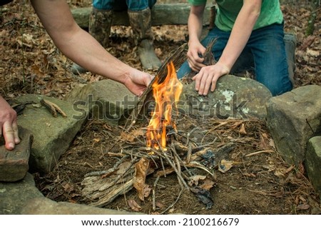 A boy building a fire in a fire-pit made out of rocks and stones- Starting a campfire- Starting a fire using a fire striker- bush craft and primitive skills- firewood and a campsite- flint striker  Royalty-Free Stock Photo #2100216679