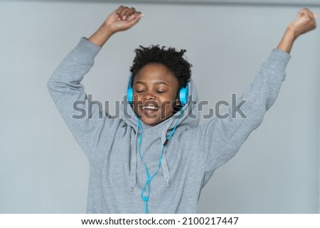 Young African American woman dancing with blue headphones, eyes closed