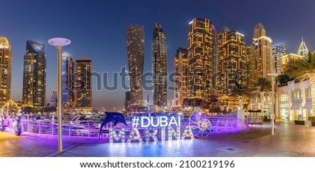 Dubai Marina logo and Harbour skyline architecture wealth luxury travel panorama at night in United Arab Emirates modern