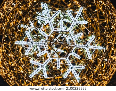 Lamps, a garland in the form of a snowflake, shine on the background of a ball on the holiday of Christmas, New Year. Winter photography.