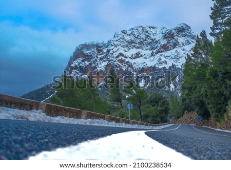 photography of a road on a snowy day with the snowy mountain in the background