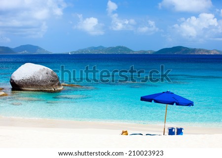 Picture perfect beach with blue umbrella, white sand and turquoise ocean water at tropical island in Caribbean