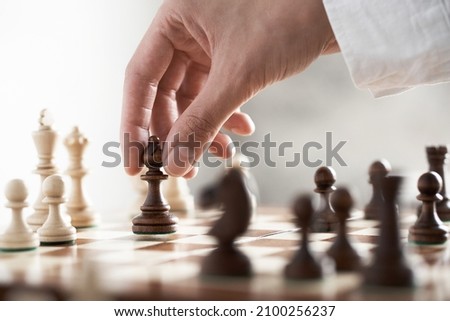 A piece for a game of chess officer an elephant makes a move soars in the air. The fingers of the hand are holding a chess piece. Chessboard cage rhombus tree in the air performing a move holds
 Royalty-Free Stock Photo #2100256237