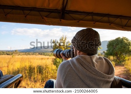 Photographer man taking a photo with his camera in an Africa Safari