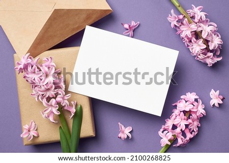 Greeting or invitation card mockup with envelope, gift box and pink hyacinth flowers over Very Peri color background