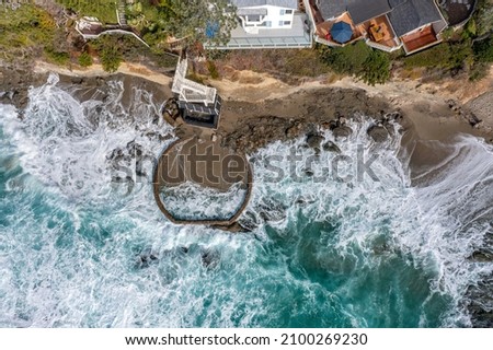Aerial view of Victoria Beach with the famous pirate's Tower, an area of Orange County California for the wealthy and affluent, shows the crashing waves and they roll over jagged shoreline reefs.


