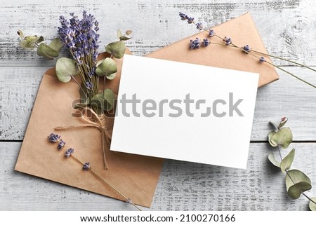 Wedding invitation or greeting card mockup with lavender and eucalyptus flowers on wooden background. Blank mockup with copy space.