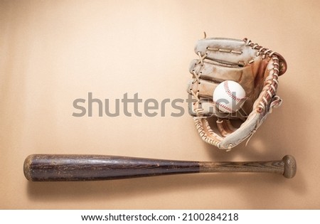 Used baseball bat, glove and ball on space of brown paper background
