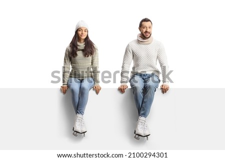 Young man and woman sitting on a blank panel and wearing ice skates isolated on white background