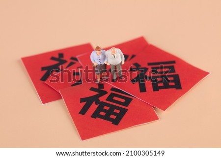Elderly couples and dolls walking on spring festival couplets with blessing. The Chinese character in the picture means: "happiness"
