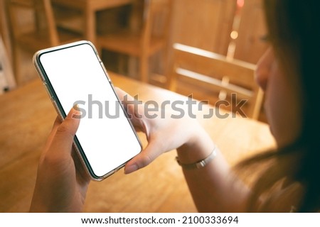 Close up women using a smartphone with an empty white screen at the wooden interior cafe. Space for social media lifestyle advertising.