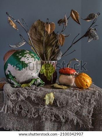 Ripe and tasty pumpkins on the table. Old ceramic jug. A bouquet of dried plants. Retro still life.